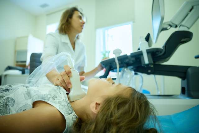 Pediatrician scanning neck. 