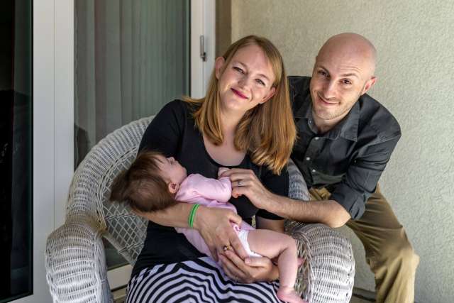 Mary and Michael Fara sitting outside while holding their baby Mabel