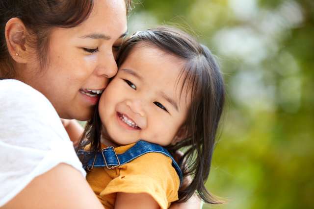 A mother holds her smiling young daughter.