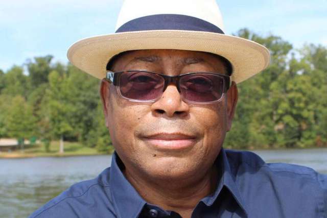 Close-up of Melvin Mann in dark blue shirt, sunglasses and straw fedora.