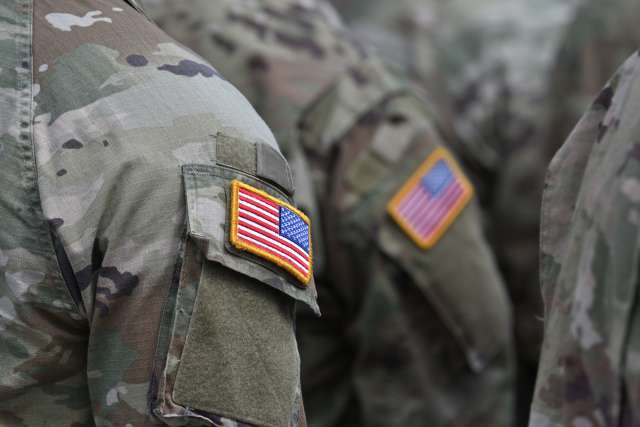 Person wearing military clothes with national symbol.
