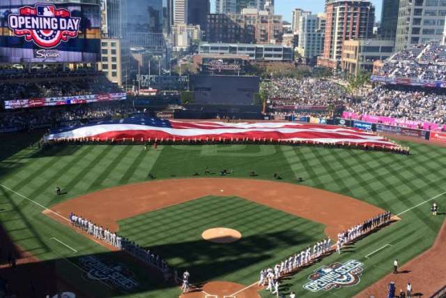 Baseball stadium pregame, teams lined up and giant flag