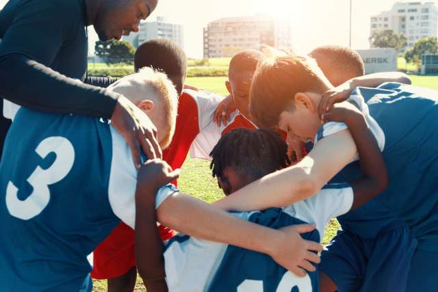 Soccer team huddling in a circle on the field
