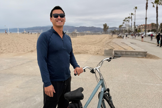 Nathan Chen with his bicycle on a beach path