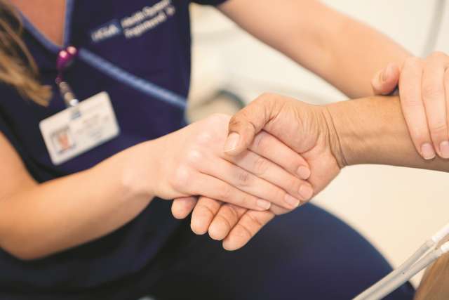 Nurse and patient holding hands