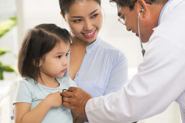 Doctor assessing child patient while mother holds her