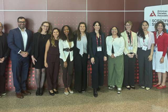 Group of professionals standing in front of a conference backdrop.