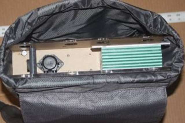 A device, which is an artificial kidney, is seen inside a black carrying bag. The device is beige with light blue pipes.