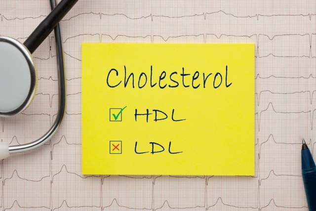 Yellow sticky note lists cholesterol with checked HDL and unchecked LDL, stethoscope nearby.