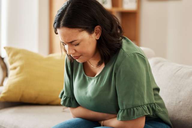 A woman holds her stomach in discomfort