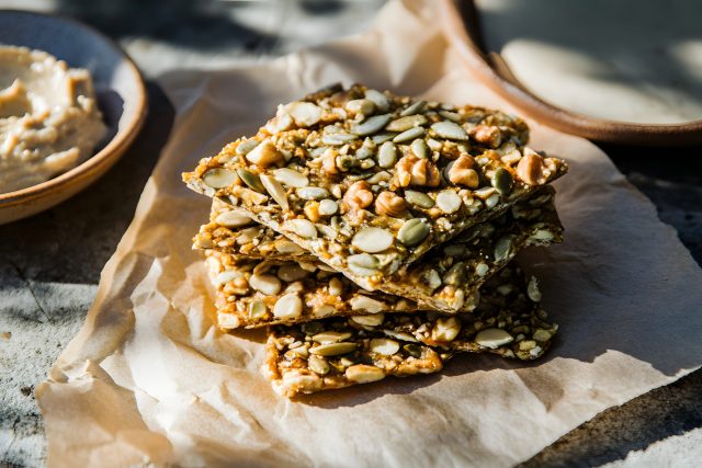 Stack of seed crackers with pumpkin seeds on parchment