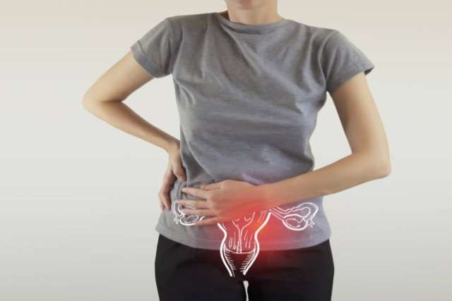 Person wearing a gray shirt holding the lower abdomen with a uterus illustration and red highlight indicating pain.