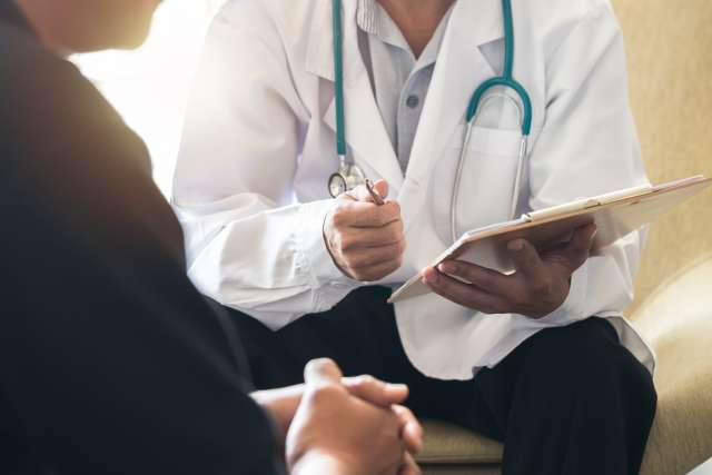 Doctor in white coat with stethoscope consulting a seated patient
