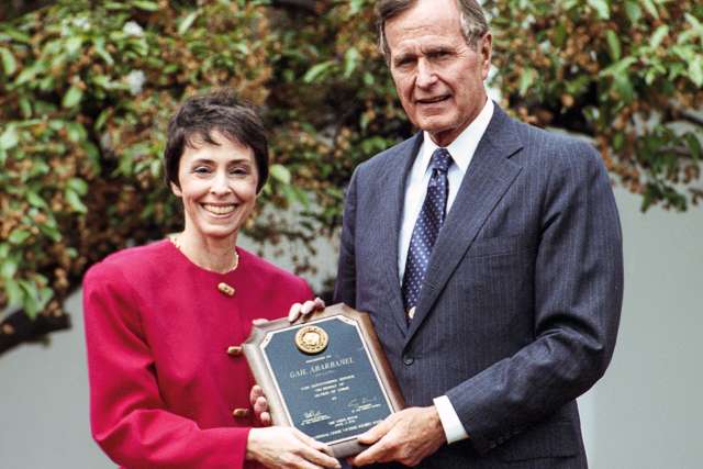 Gail Abarbanel and George H.W. Bush pose for a photo with a plaque