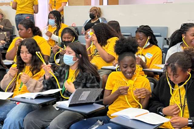 Middle‑school students at a cardiovascular health outreach event at Charles Drew University receive plastic stethoscopes