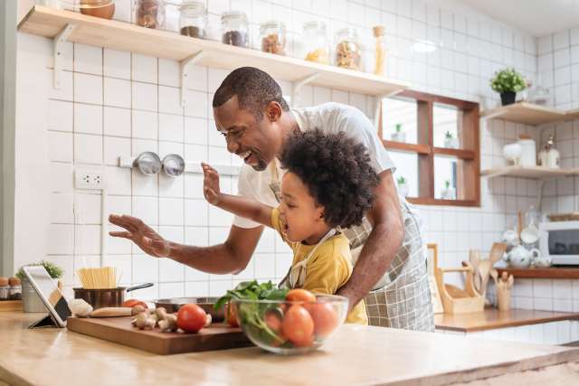 father and son cooking in kitchen while looking at iPad