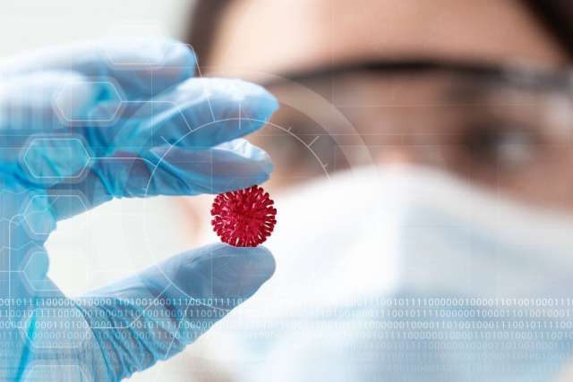 Scientist in mask and gloves holding petri dish with red virus model