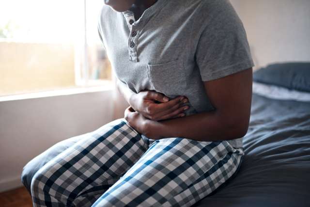 A person holds their stomach in discomfort