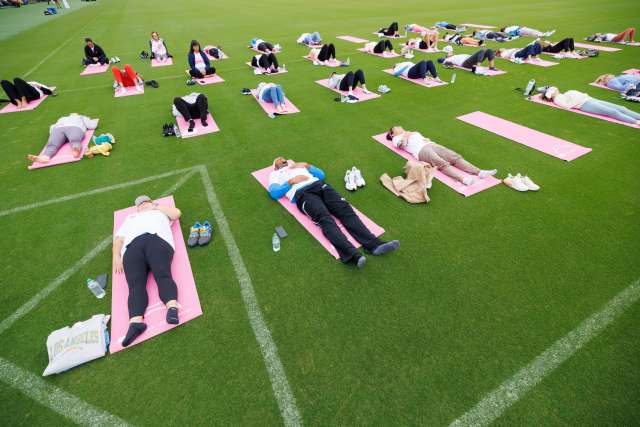 Cancer patients and survivors relax on pink yoga mats on the field at the Chargers practice facility