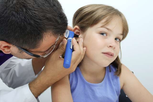 Adult examining child's ear with otoscope