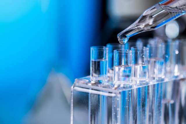 Researcher using a pipette to fill up test tubes