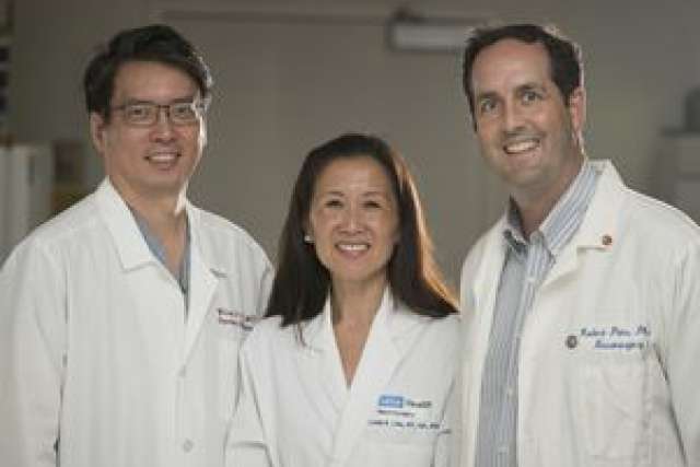 Three healthcare professionals in lab coats, standing together in a clinical setting.