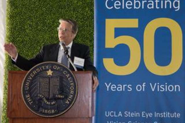 Man speaking at a podium with a seal, celebrating 50 years of vision at UCLA.