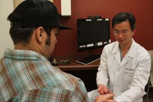 Dr. Daniel Lu checking patient's hand