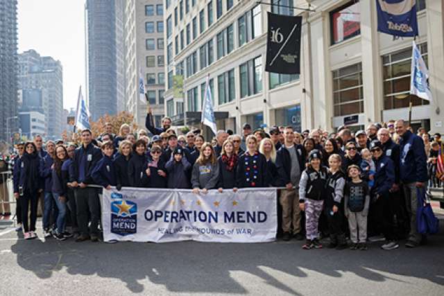 UCLA Operation Mend team and veterans marching in the 2019 Veterans Day Parade holding a banner that reads “Healing the Wounds of War.”