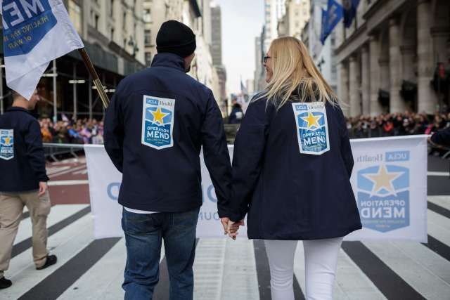 Two people wear Operation Mend jackets during a parade