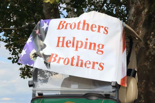 Sign reading "Brothers Helping Brothers" attached to a golf cart
