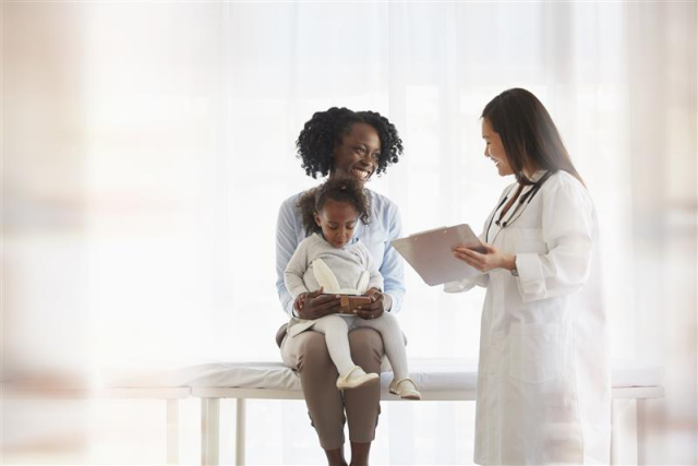 A black female patient talking with an asian female doctor.