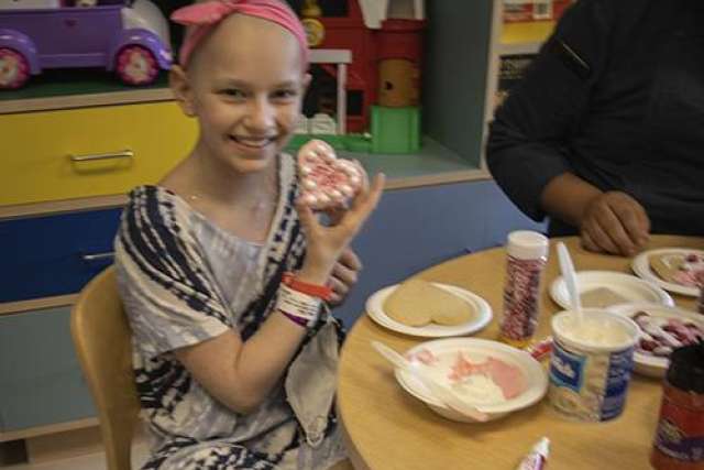 Felicia Amoia at UCLA Health smiling, seated at a table holding a decorated cookie