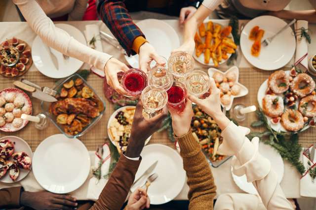 a photo of people cheers-ing holiday beverages at a dinner table