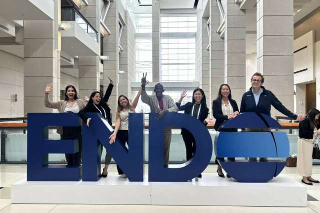 Group of people posing on large blue letters spelling ENDO in a bright atrium