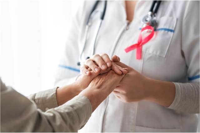 Female physician holds the hand of a breast cancer patient