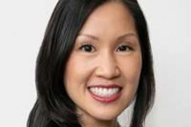 Headshot of a person with long dark hair and a neutral background.