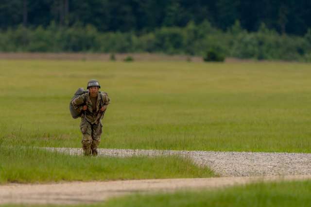 A West Point cadet is suited up and running through a field.