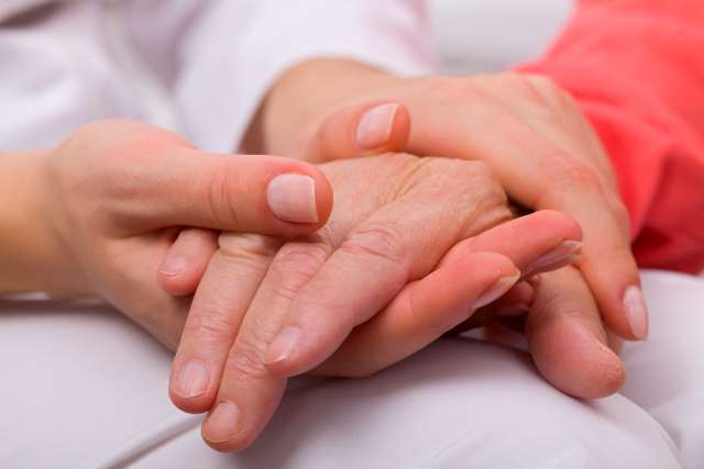 Two hands clasped, one gently holding the other