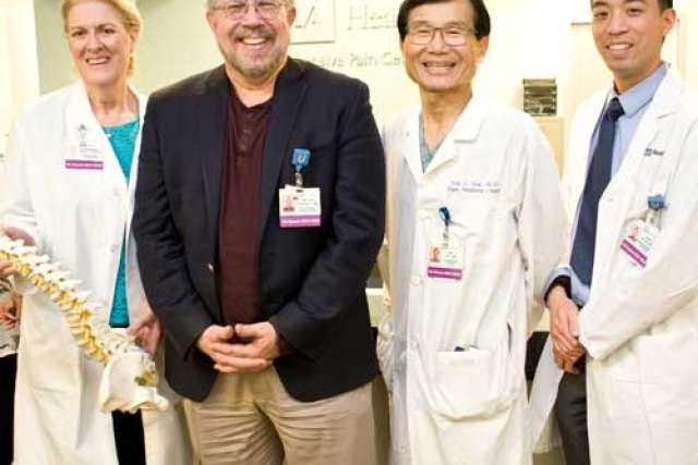 Team of five medical staff smiling in clinic.
