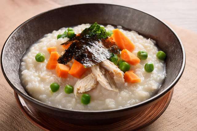 Rice Porridge in a Bowl with Carrots and Peas