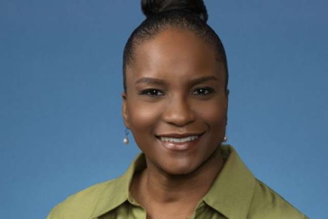 Woman wearing a green shirt against a blue background.