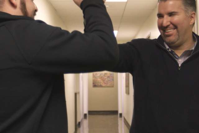 Two men high fiving in a hallway