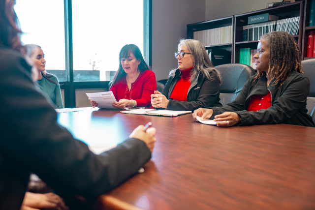 VA Personnel in a conference room with a window and a bookcase in the background.