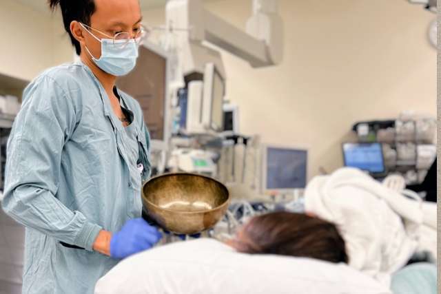 Nurse anesthetist Huy Vo plays a Tibetan singing bowl for a patient before administering anesthesia. 