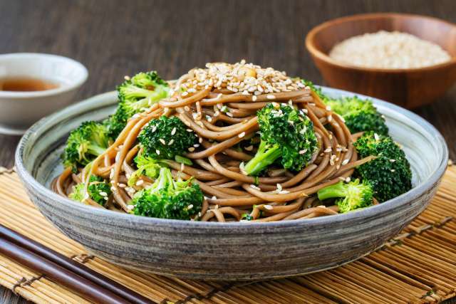 Garlic Sesame Soba Noodles on a bamboo placemat in a grey bowl