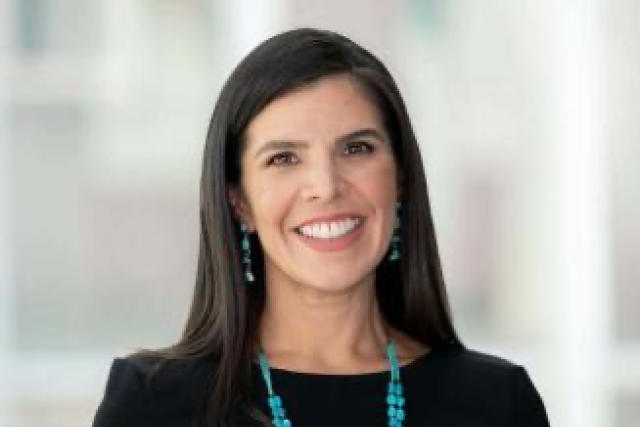 Smiling woman headshot wearing a black top with turquoise necklace and earrings