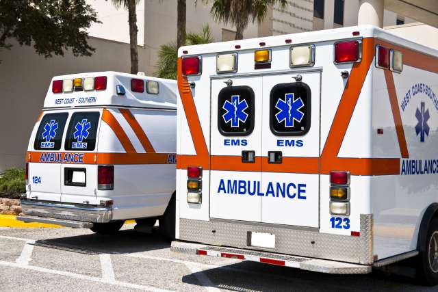 EMS Emergency trucks: two ambulances seen from rear with EMS logos and lights