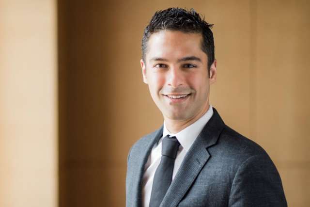 Business professional in a suit against a wooden backdrop.