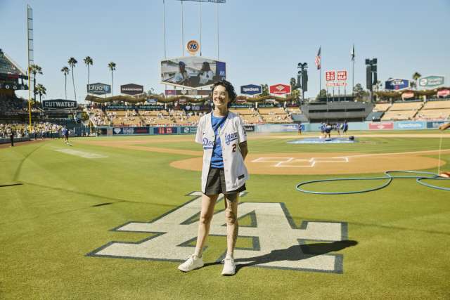 A woman stands near the LA logo on the field at UNIQLO Field at Dodger Stadium.
